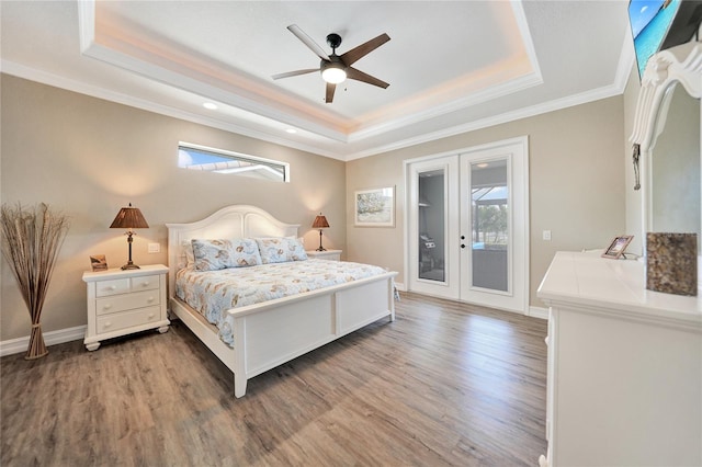 bedroom with a tray ceiling, access to exterior, ceiling fan, french doors, and hardwood / wood-style flooring