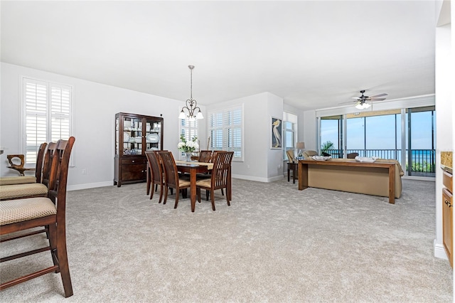 carpeted dining space with ceiling fan with notable chandelier