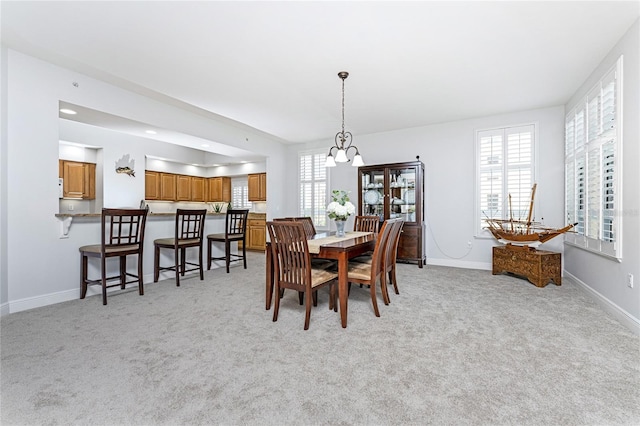 dining room with light carpet and a chandelier