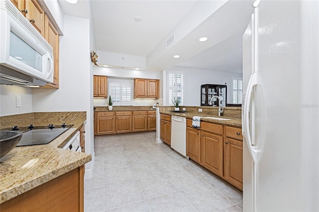 kitchen with light stone counters, sink, light tile patterned flooring, and white appliances