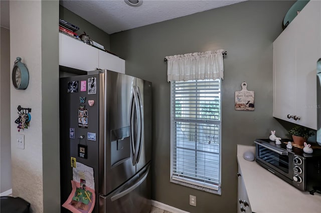 kitchen with stainless steel refrigerator with ice dispenser and white cabinetry