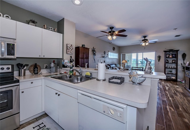 kitchen with ceiling fan, white cabinetry, dark wood-type flooring, stainless steel appliances, and kitchen peninsula