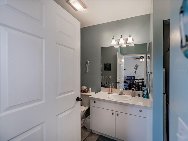 bathroom featuring ceiling fan, toilet, vanity with extensive cabinet space, and tile flooring