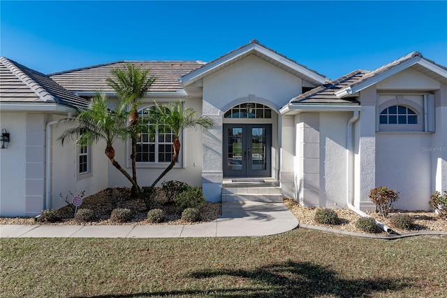 doorway to property featuring french doors and a lawn