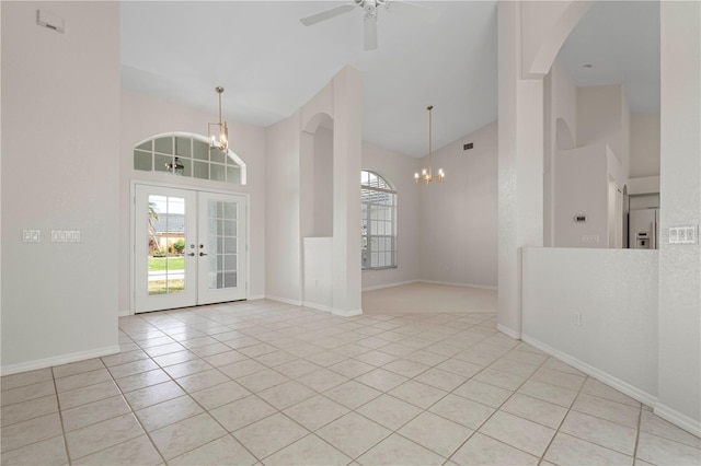 entryway featuring french doors, ceiling fan with notable chandelier, high vaulted ceiling, and light tile patterned floors