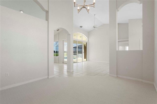 carpeted empty room featuring ceiling fan with notable chandelier and high vaulted ceiling