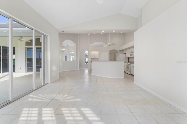 unfurnished living room with ceiling fan with notable chandelier, light tile patterned flooring, and vaulted ceiling