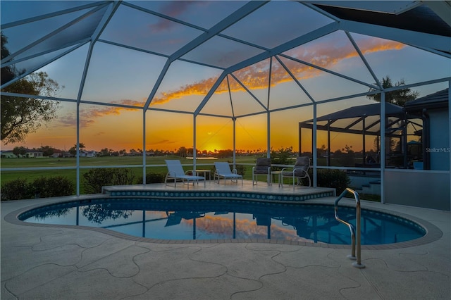 pool at dusk featuring a patio and glass enclosure