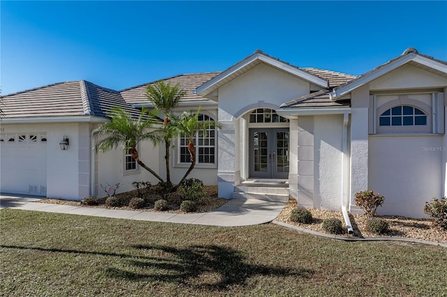 view of front of property featuring french doors, a front yard, and a garage