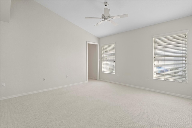 spare room featuring ceiling fan, light colored carpet, and vaulted ceiling