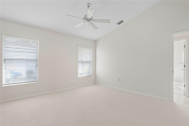 carpeted spare room featuring a wealth of natural light, ceiling fan, and vaulted ceiling