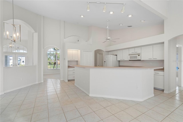 kitchen featuring white cabinetry, ceiling fan with notable chandelier, a high ceiling, and white appliances