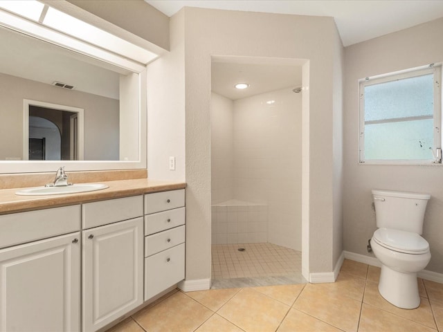 bathroom featuring toilet, a tile shower, large vanity, and tile flooring