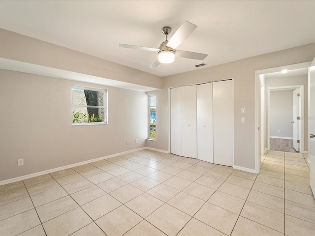 unfurnished bedroom featuring light tile flooring, a closet, and ceiling fan