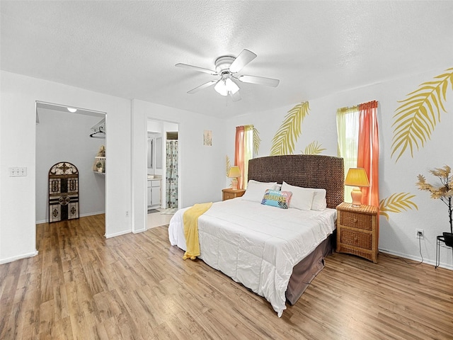 bedroom featuring a textured ceiling, ensuite bath, ceiling fan, and light hardwood / wood-style flooring