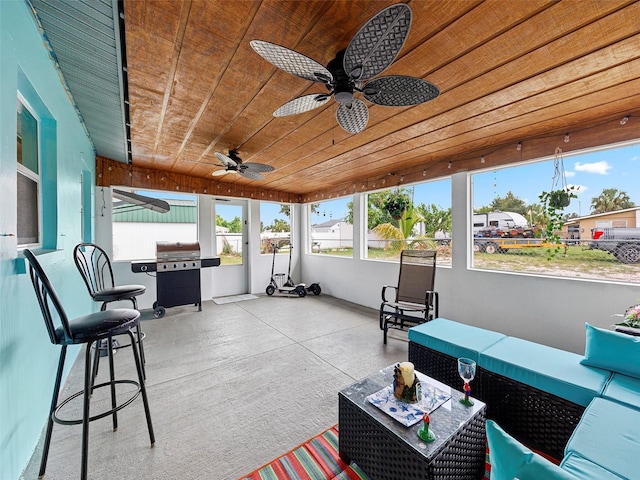 sunroom with ceiling fan and wood ceiling