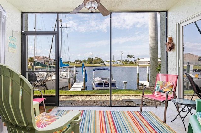 sunroom / solarium featuring a water view, a ceiling fan, and a healthy amount of sunlight