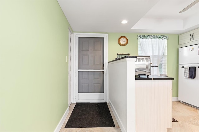 kitchen with a tray ceiling, ceiling fan, and white fridge