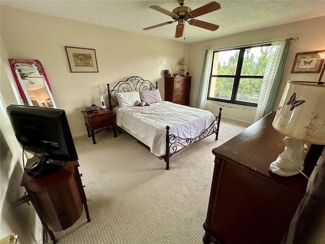 bedroom with ceiling fan, light colored carpet, and a textured ceiling