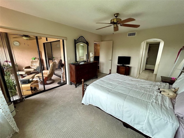 bedroom with ceiling fan, light colored carpet, and a textured ceiling