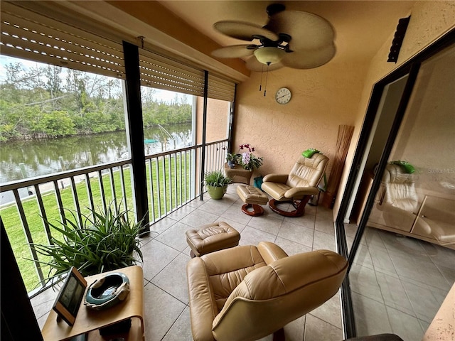 sunroom / solarium with ceiling fan and a water view