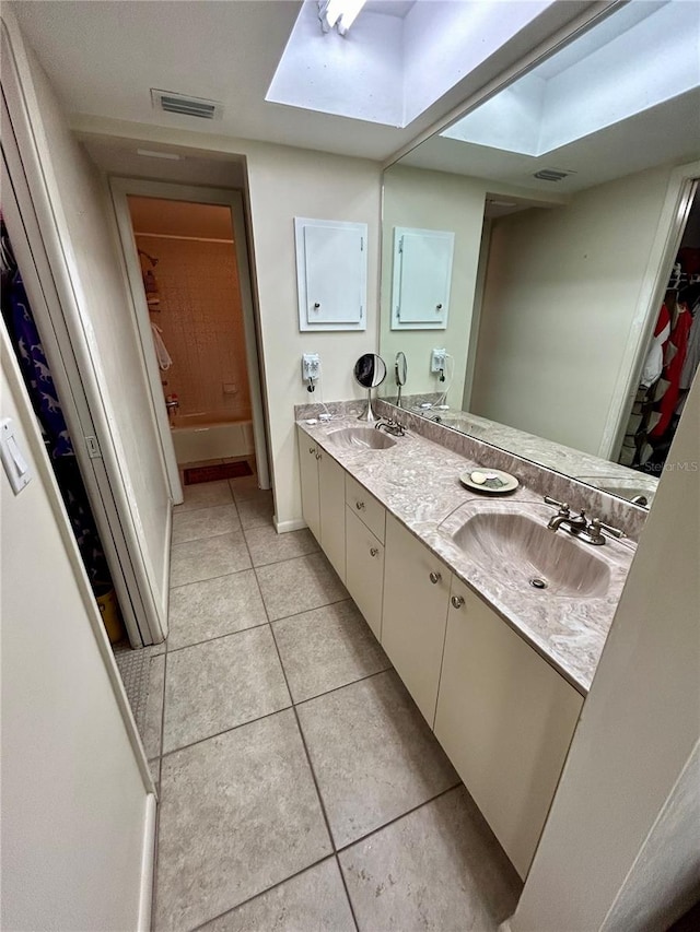 bathroom with vanity, a skylight, and tile patterned floors