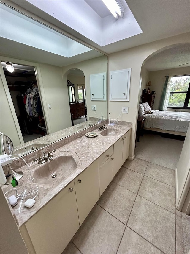 bathroom with a skylight, tile patterned flooring, and vanity