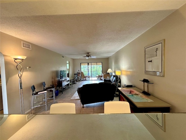 tiled living room with ceiling fan and a textured ceiling