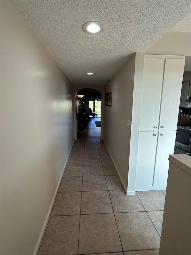 hallway with light tile patterned floors and a textured ceiling