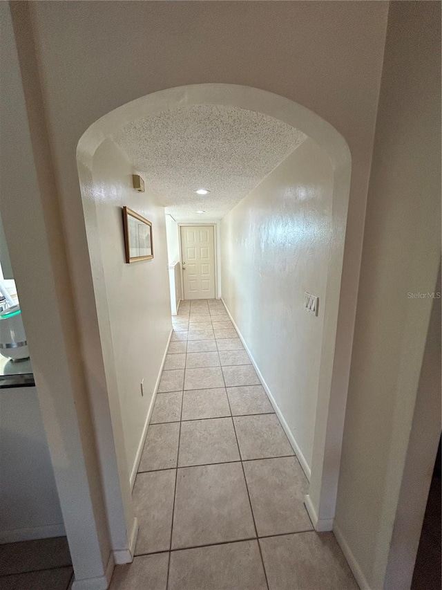 corridor with light tile patterned floors and a textured ceiling