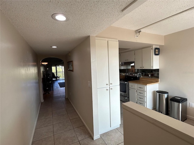 hall with a textured ceiling and light tile patterned flooring