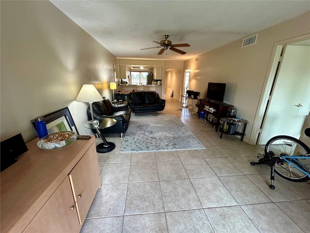 tiled living room featuring ceiling fan and a textured ceiling