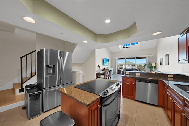 kitchen featuring light tile flooring, dark stone countertops, a kitchen island, and appliances with stainless steel finishes