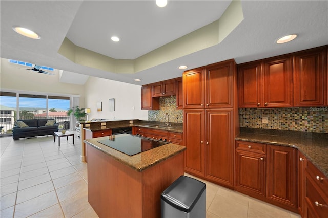 kitchen with backsplash, black electric cooktop, dark stone countertops, and a center island