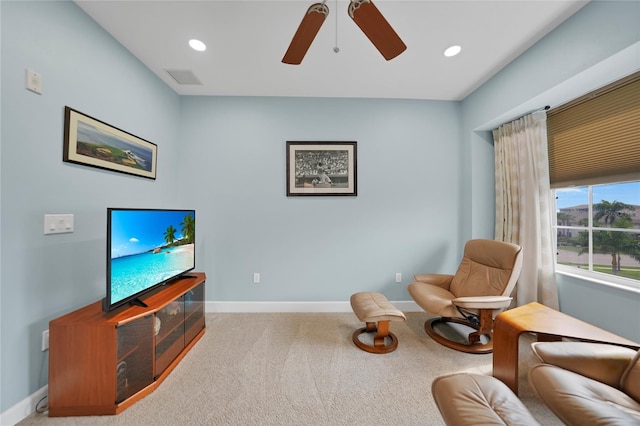 living area with light carpet and ceiling fan