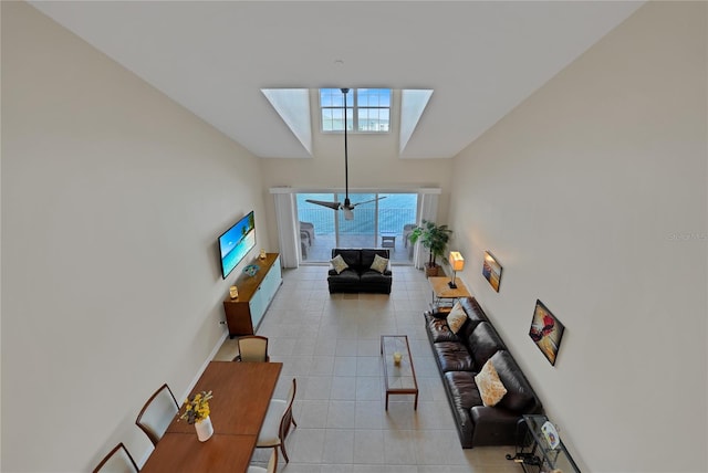 tiled living room with ceiling fan and a towering ceiling