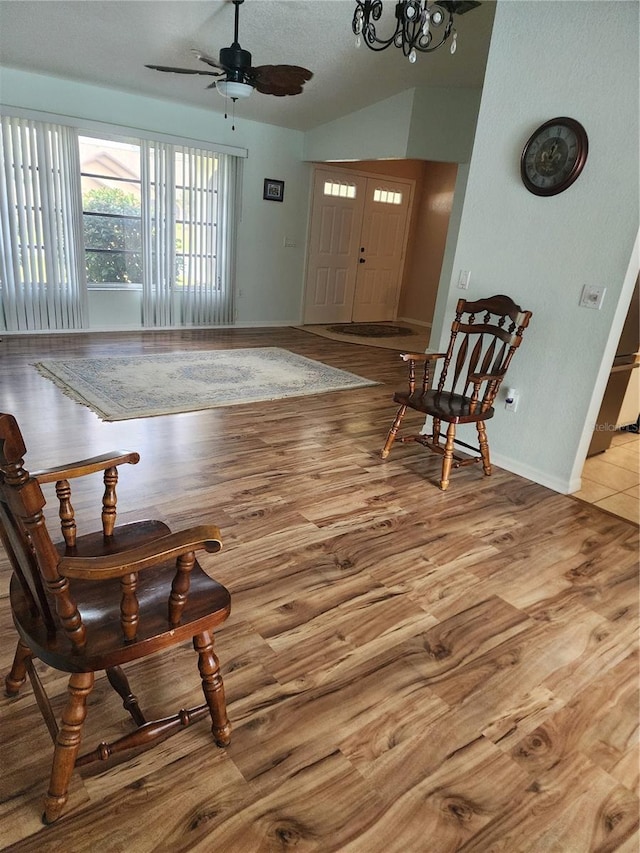 entrance foyer featuring vaulted ceiling, light hardwood / wood-style floors, a textured ceiling, and ceiling fan with notable chandelier