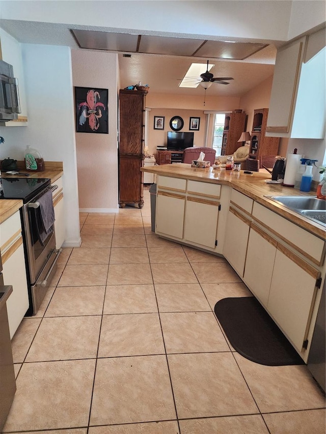 kitchen with light tile floors, ceiling fan, cream cabinets, appliances with stainless steel finishes, and sink