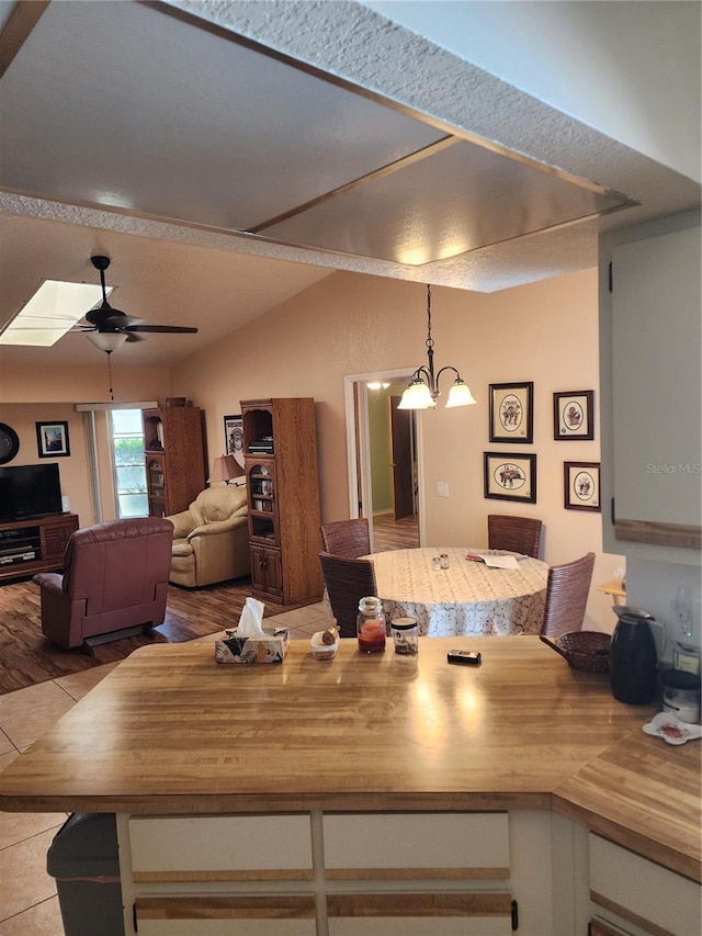 interior space featuring a skylight, wood counters, hanging light fixtures, and ceiling fan with notable chandelier