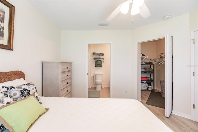 bedroom with a closet, light hardwood / wood-style flooring, connected bathroom, ceiling fan, and a walk in closet