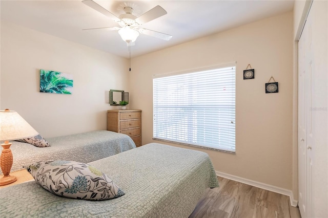 bedroom with a closet, light hardwood / wood-style flooring, and ceiling fan