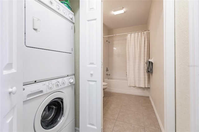 laundry area with stacked washer / dryer and light tile flooring