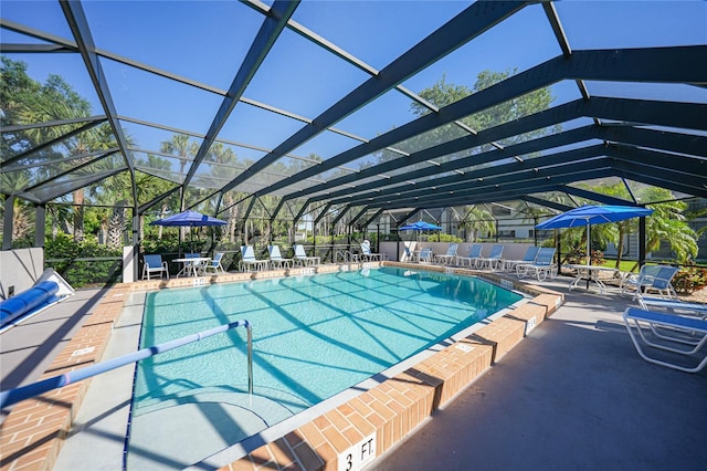 view of swimming pool featuring glass enclosure and a patio