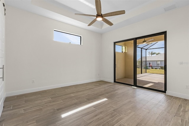 spare room featuring ceiling fan, a tray ceiling, and hardwood / wood-style flooring