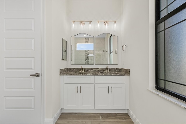 bathroom featuring wood-type flooring, large vanity, and dual sinks