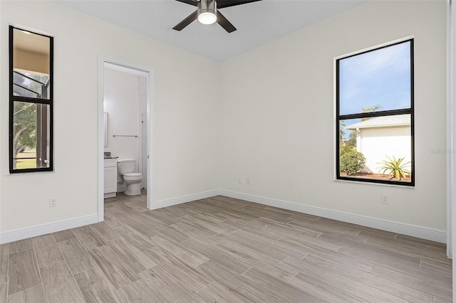 unfurnished bedroom featuring ensuite bath, light hardwood / wood-style floors, and ceiling fan