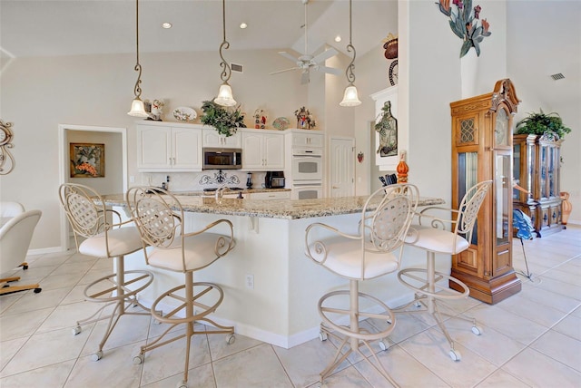 kitchen with white cabinets, light tile patterned floors, decorative backsplash, and light stone countertops