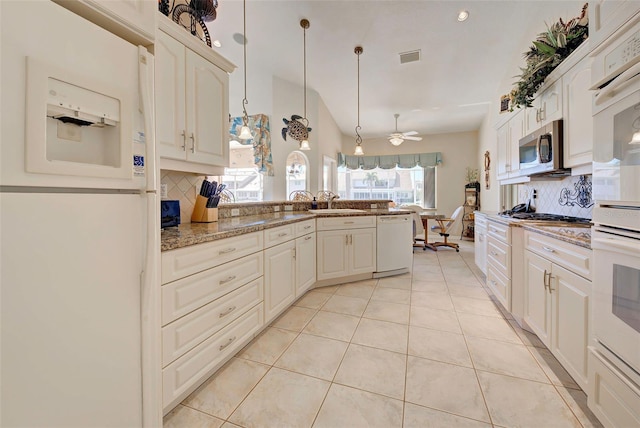 kitchen with tasteful backsplash, light stone counters, pendant lighting, and white appliances