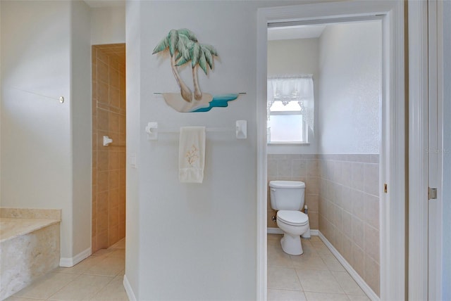 bathroom with tile patterned flooring, toilet, and tile walls