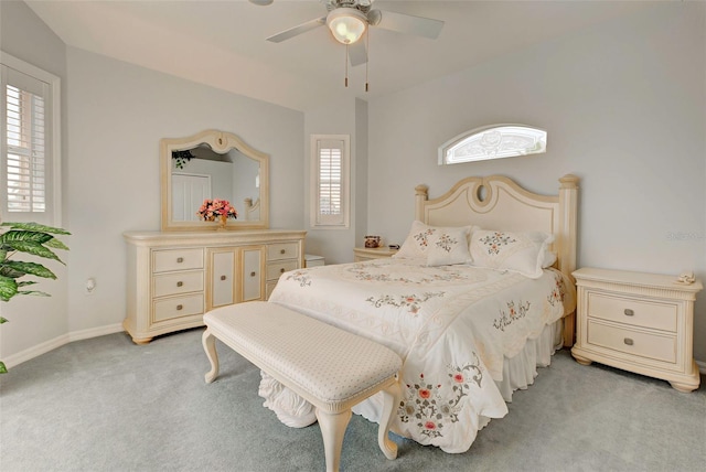 carpeted bedroom with multiple windows, ceiling fan, and vaulted ceiling